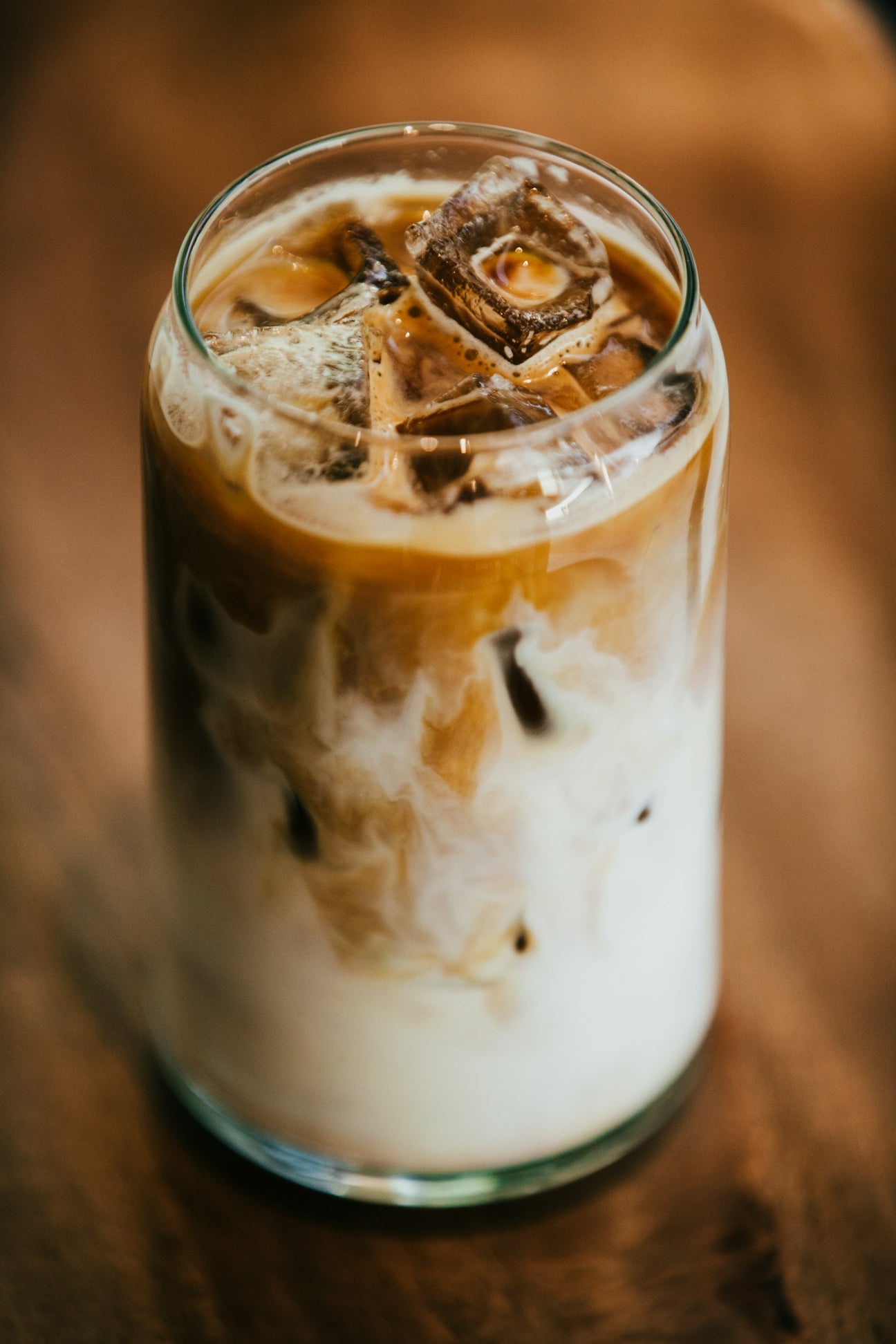 An iced latte in a tall glass with milk settling through the ice