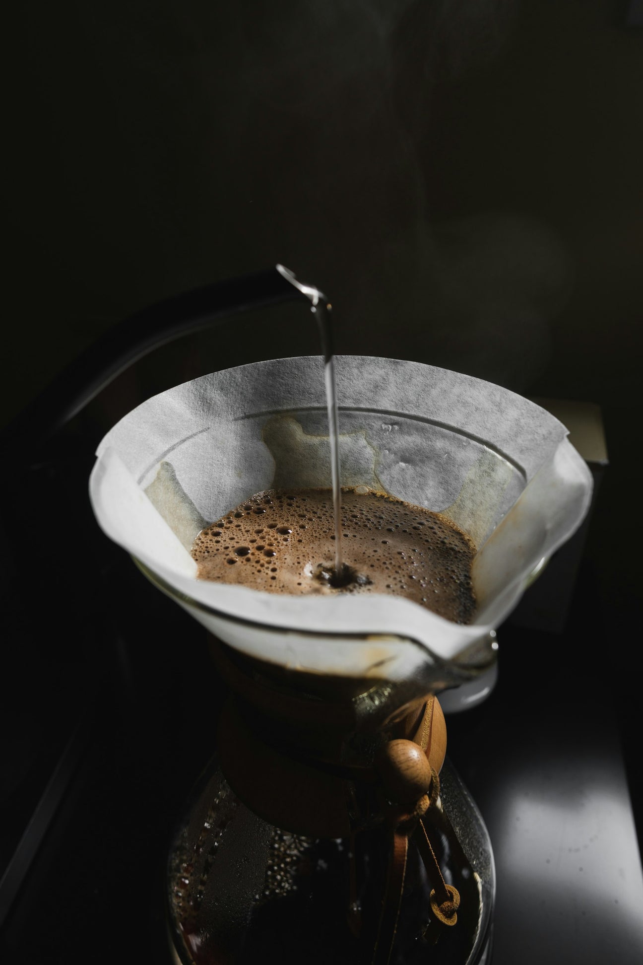 A thin stream of water poured onto a bed of coffee in a paper filter