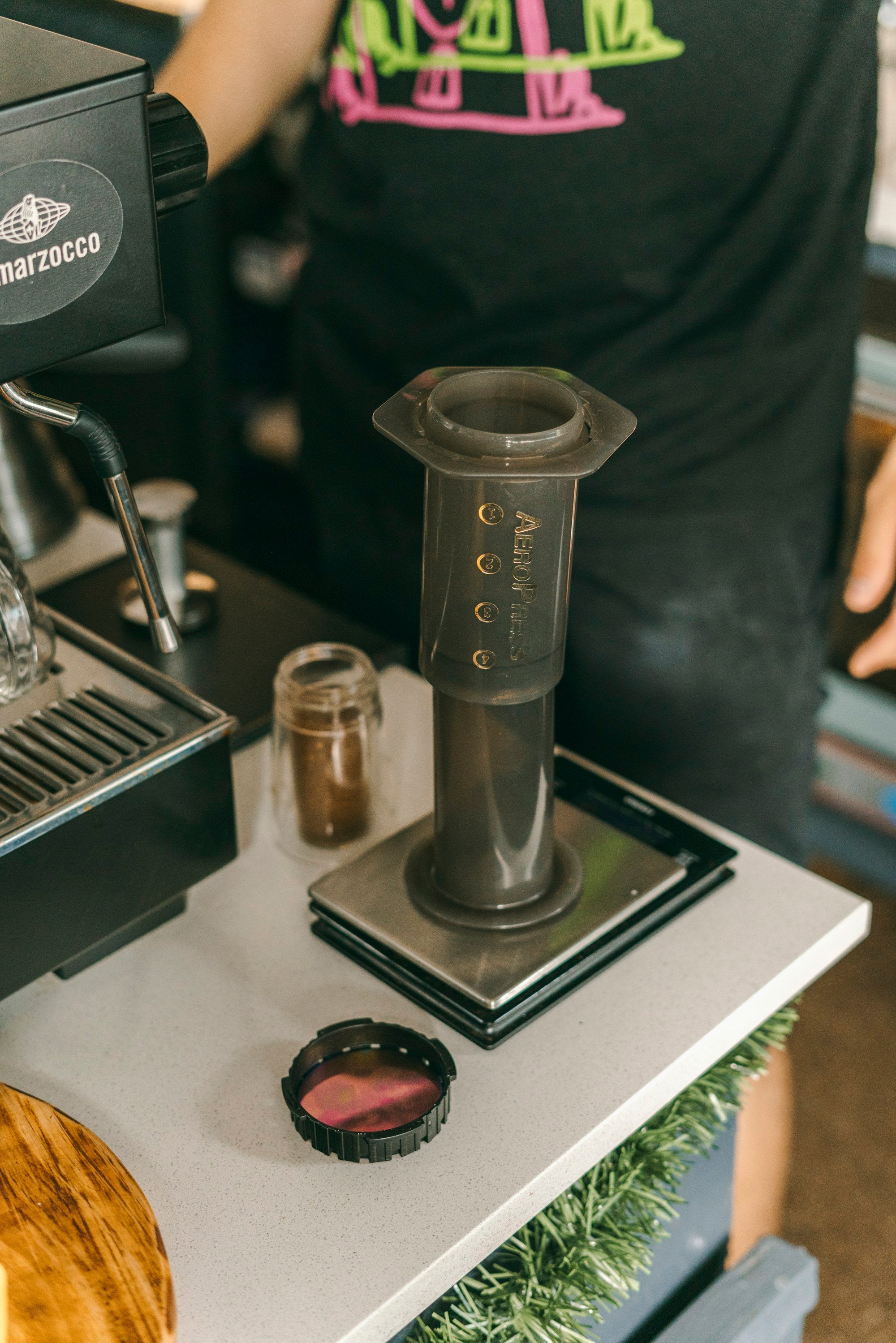 An AeroPress standing on a scale on a café counter