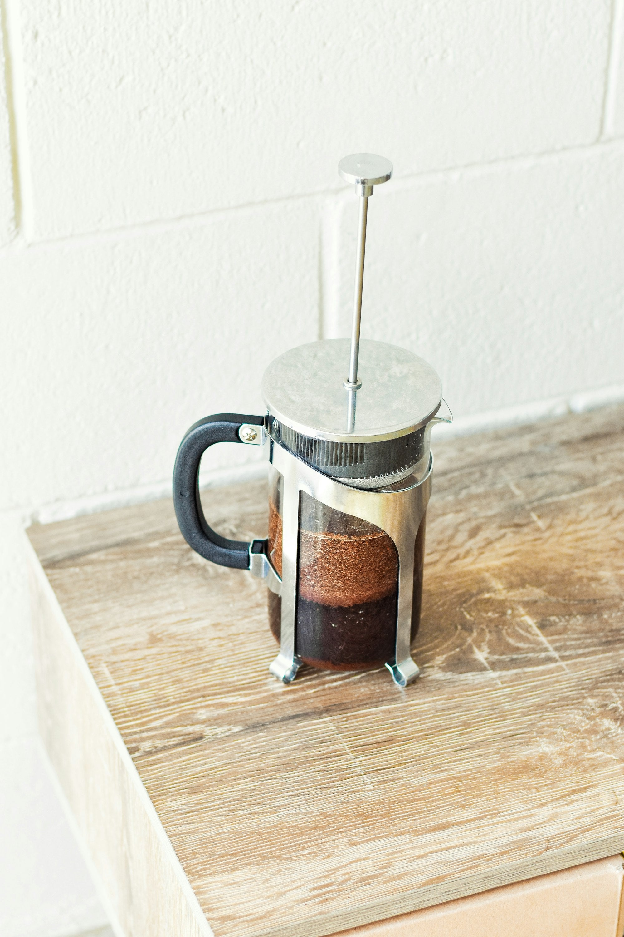 A french press of brewed coffee on a wooden table