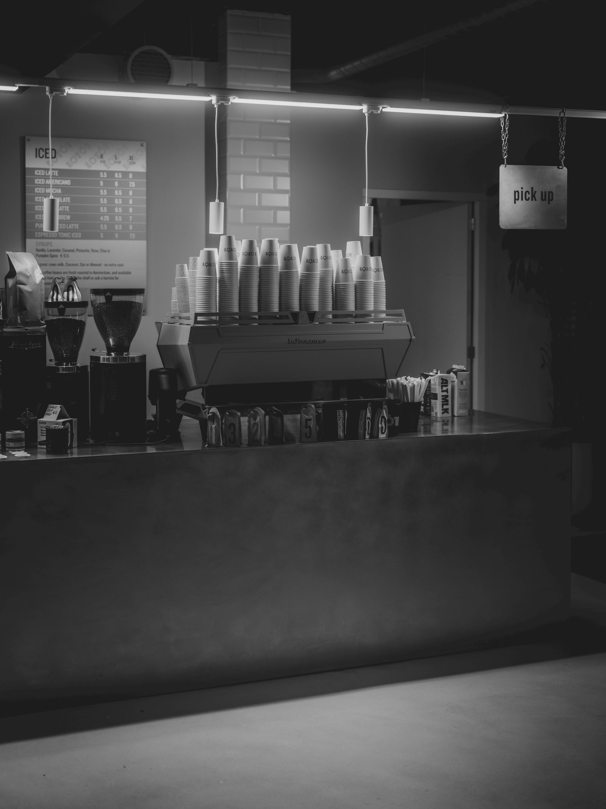 A café counter with an espresso machine and stacked cups